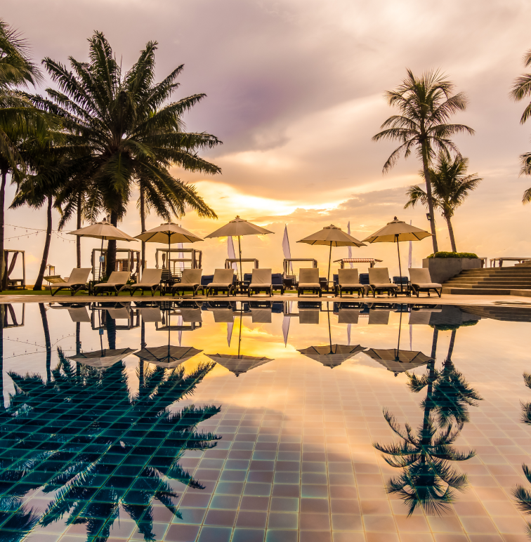 Luxury resort pool with palm trees at sunset